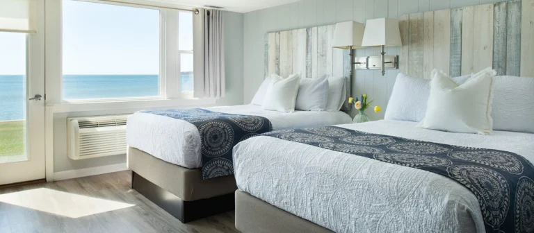 Oceanfront guest room with two beds and direct lawn access.