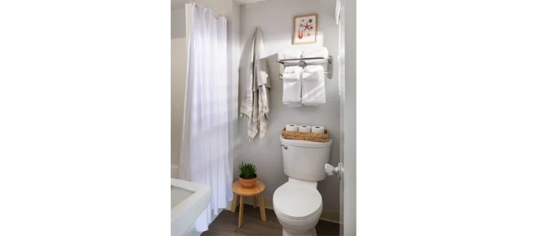 Bright guest bathroom with walk-in shower, fresh towels, and coastal-inspired decor.