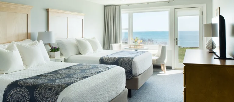 Upper building guest room with two beds, oceanfront lawn access, and views of the Atlantic Ocean.