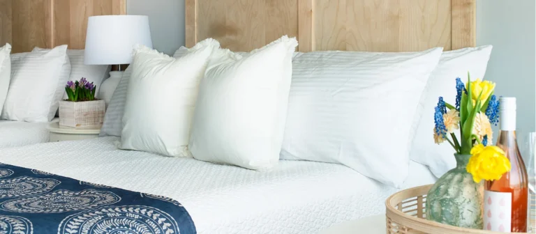 Coastal-inspired guest room details with plush bedding, fresh flowers, and bright natural light.