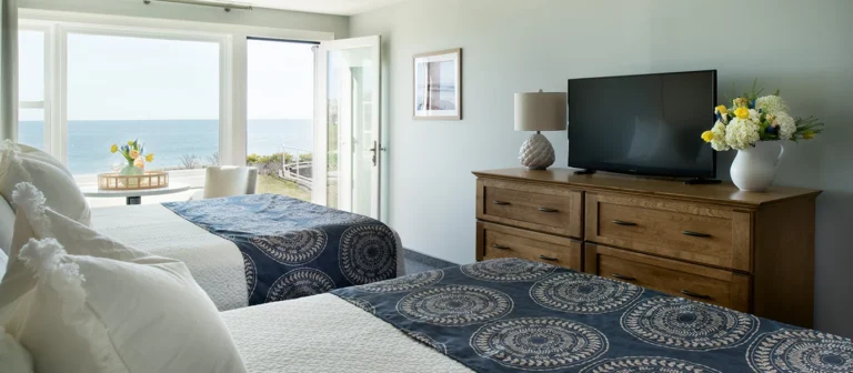 Bright upper building first-floor guest room with two beds, ocean views, and direct outdoor access.